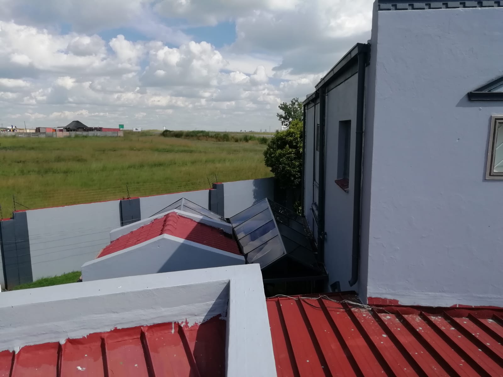 Painted parapet walls and sealed red roof sheeting on a modern home