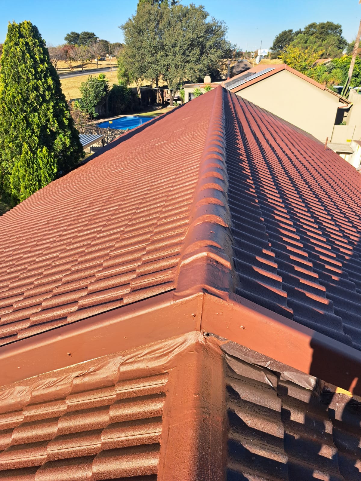 Freshly sealed terracotta tiled roof with newly coated ridge and gutters