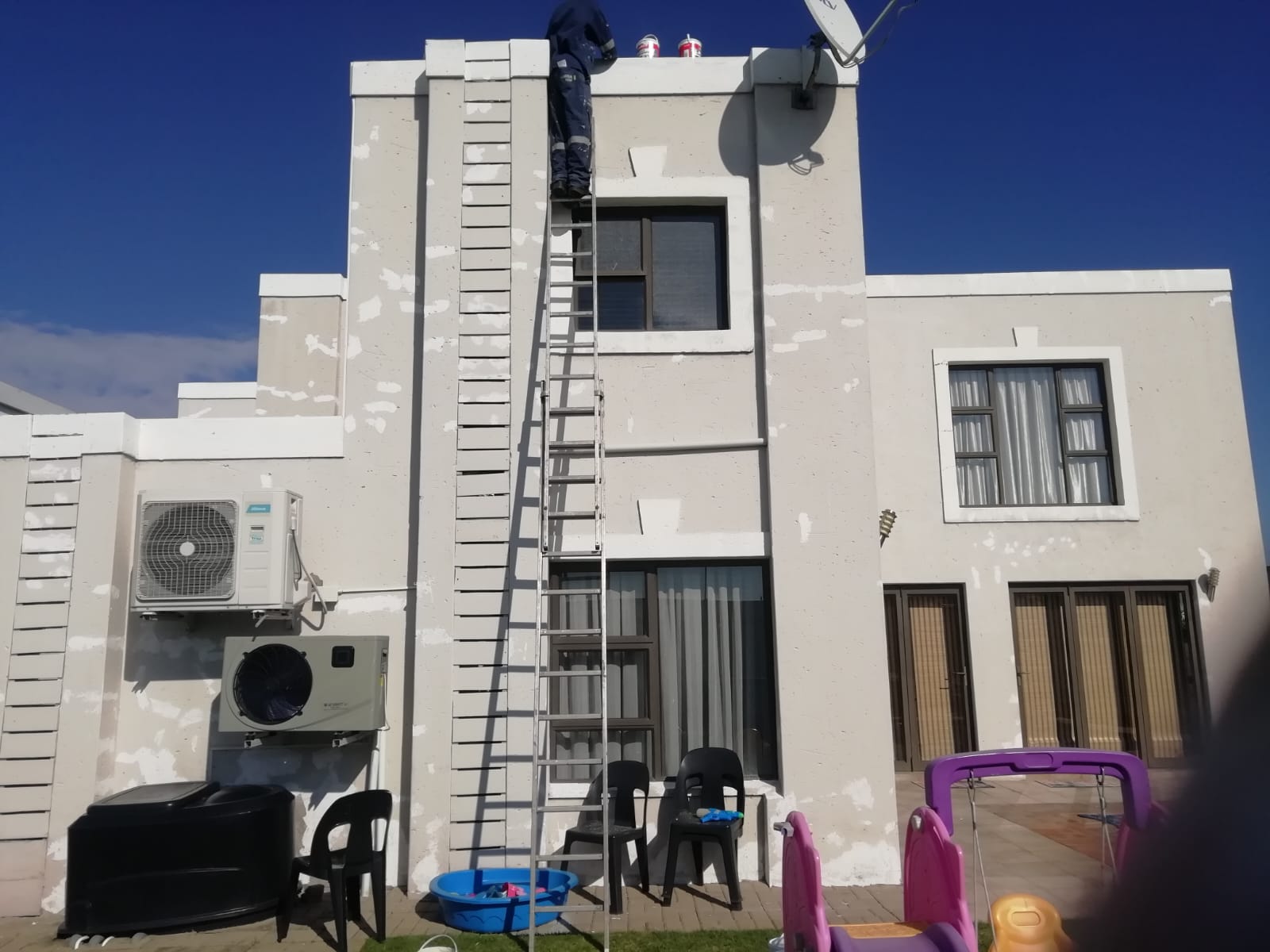 Exterior wall preparation and painting in progress on a double-storey home