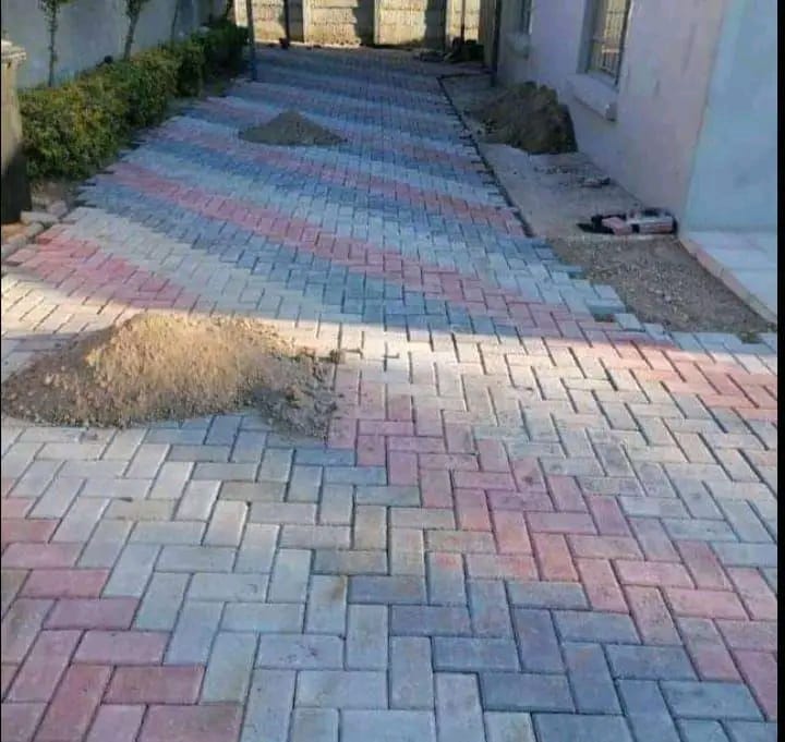 Multi-tone brick paving being laid along a residential side passage