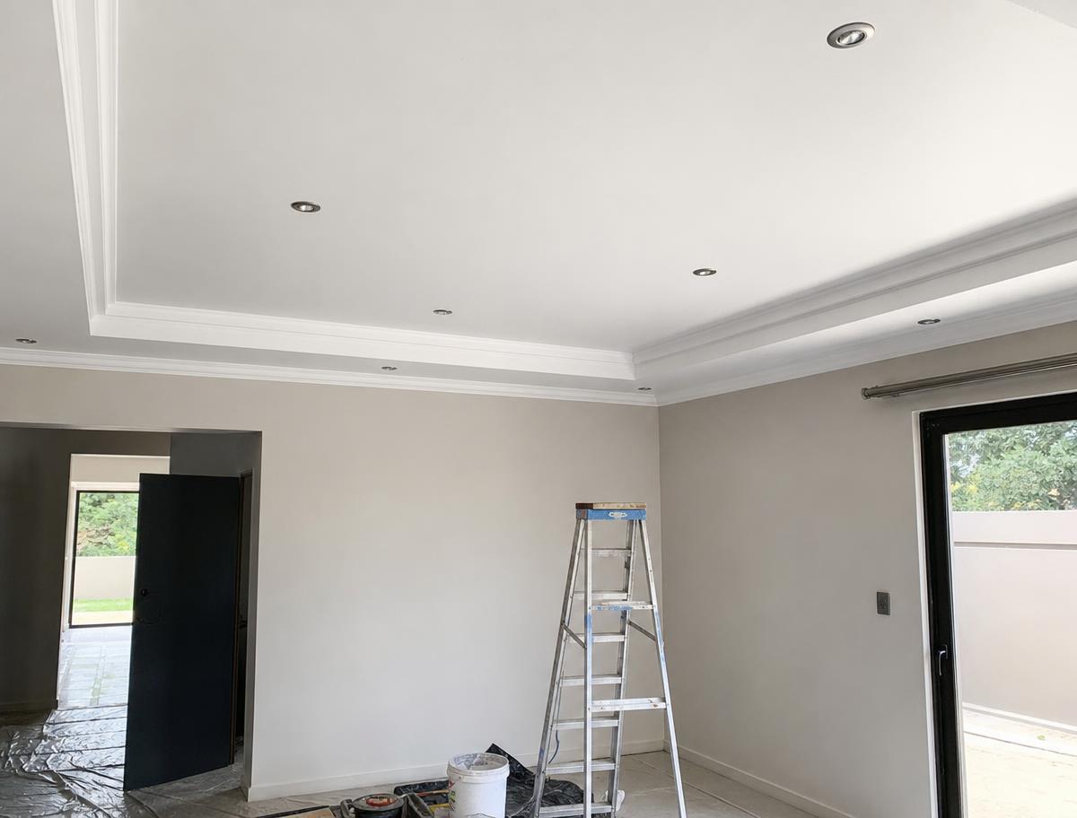 Newly installed residential ceiling with cornices and recessed downlights